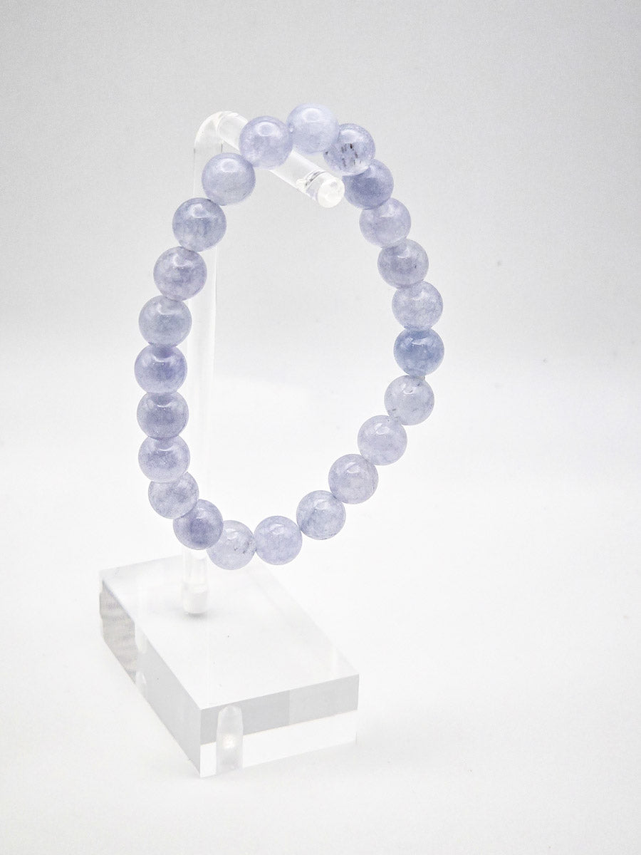 Aquamarine bracelet displayed on a clear acrylic stand, showcasing the stone's properties for calming and emotional balance.