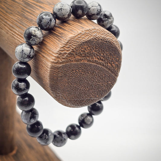 Snowflake Obsidian Beaded Bracelet on Wood Stand - Symbol of Balance and Clarity.