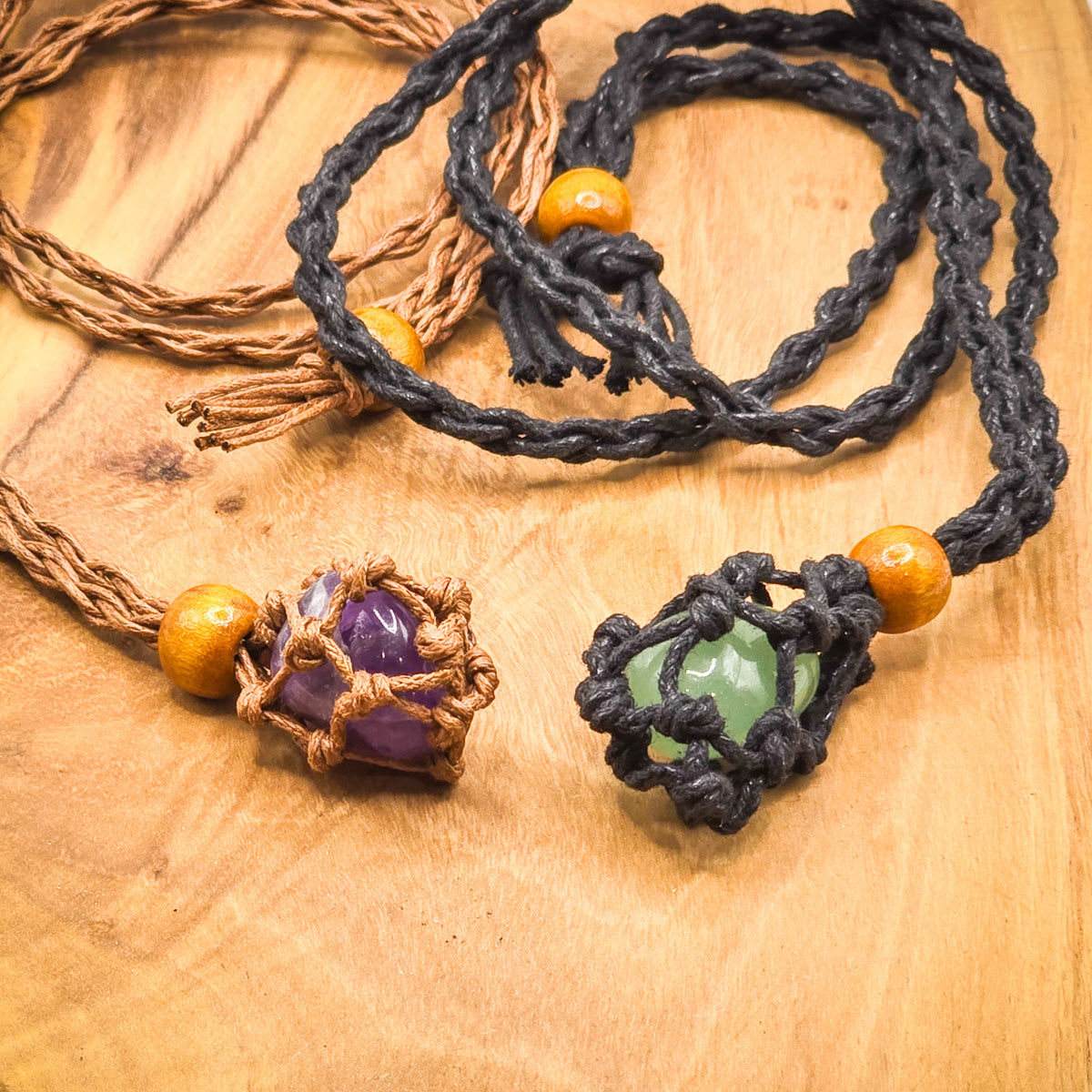 Necklaces from the Chakra Stone Kit with a stone displayed in each, on wood