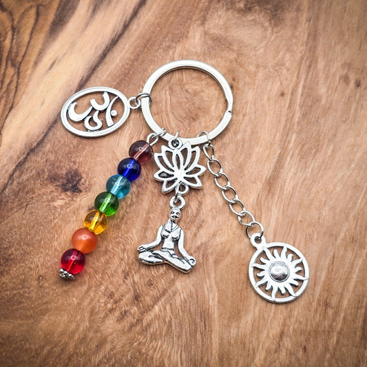 Chakra Keychain with rainbow beads and yoga-inspired charms including an Ohm symbol, meditating woman, lotus flower, and sun