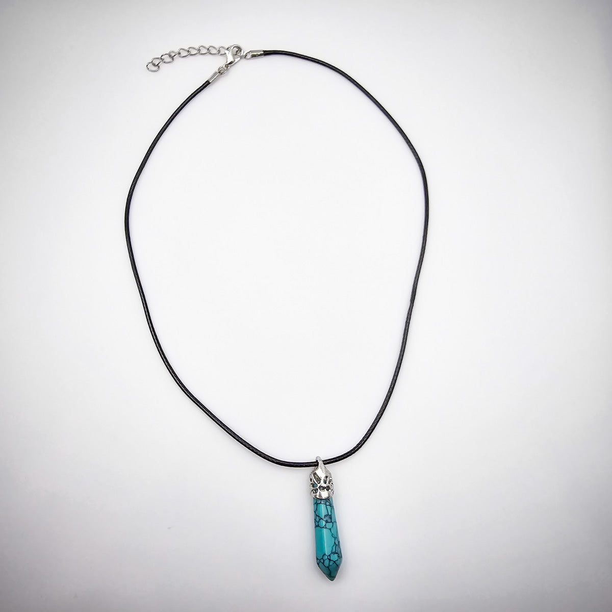 Full view of the Turquoise pendant necklace against a white background, emphasizing the elegance of the black cord and the pendant's captivating color.