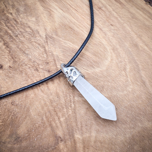 Clear Quartz hexagonal column pendant on black cord, displayed on wood, highlighting its transparent elegance and geometric precision.