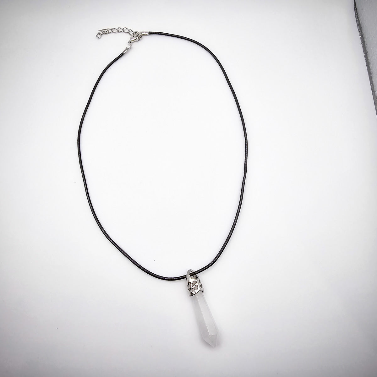 Entire Clear Quartz pendant necklace against a white background, accentuating the black cord and the crystal's luminous simplicity.