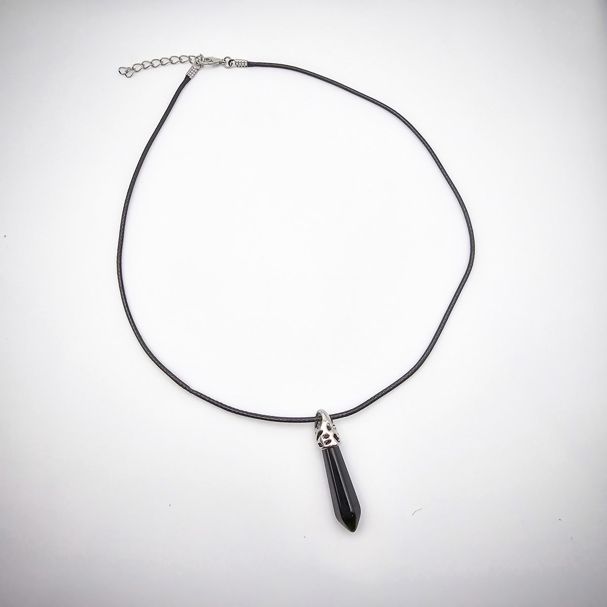 The entire Onyx pendant necklace against a white background, emphasizing the striking contrast of the black cord and the pendant's bold, protective essence.