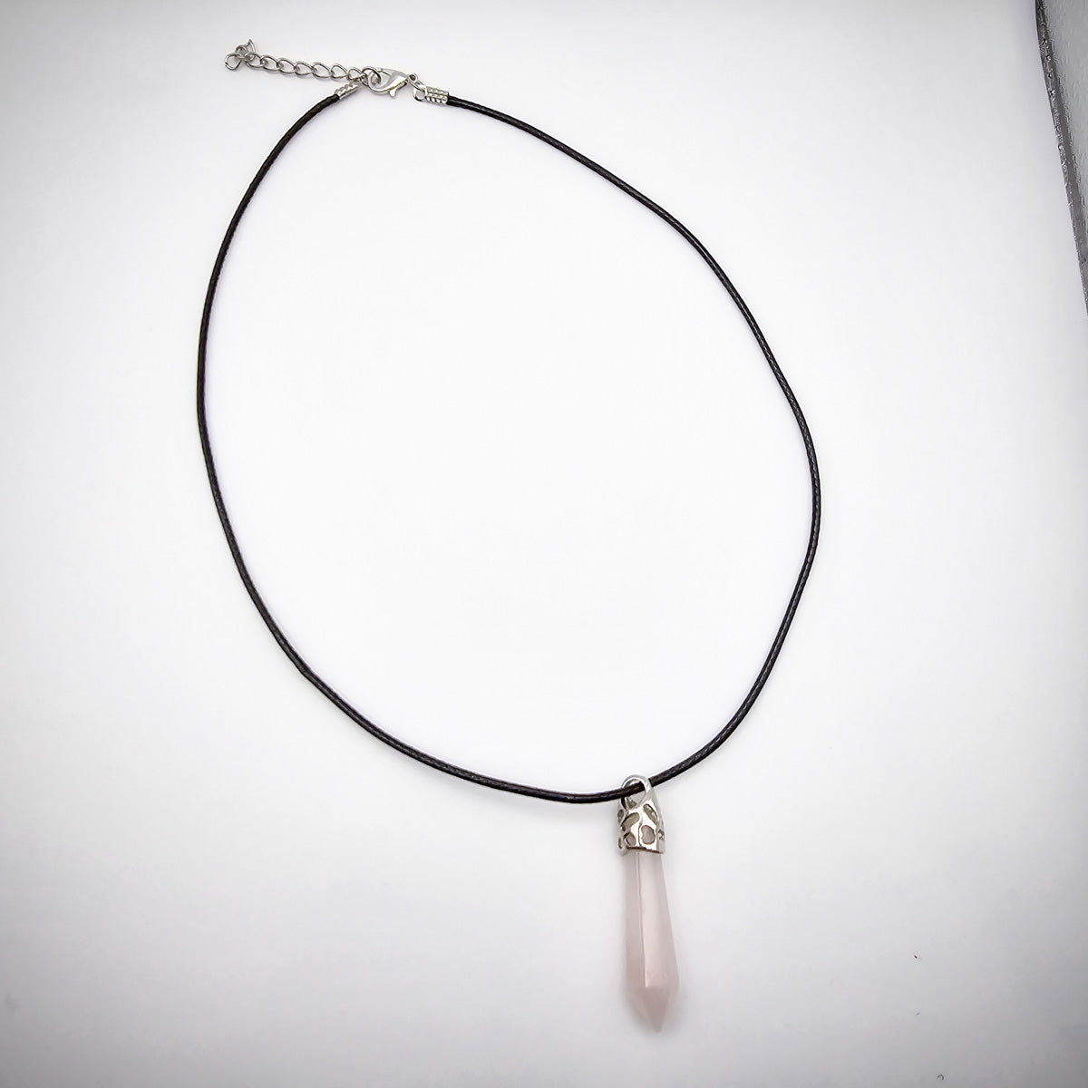 The entire Rose Quartz pendant necklace displayed on a white background, emphasizing the beauty of the black cord and the pendant's serene presence.The entire Rose Quartz pendant necklace displayed on a white background, emphasizing the beauty of the black cord and the pendant's serene presence