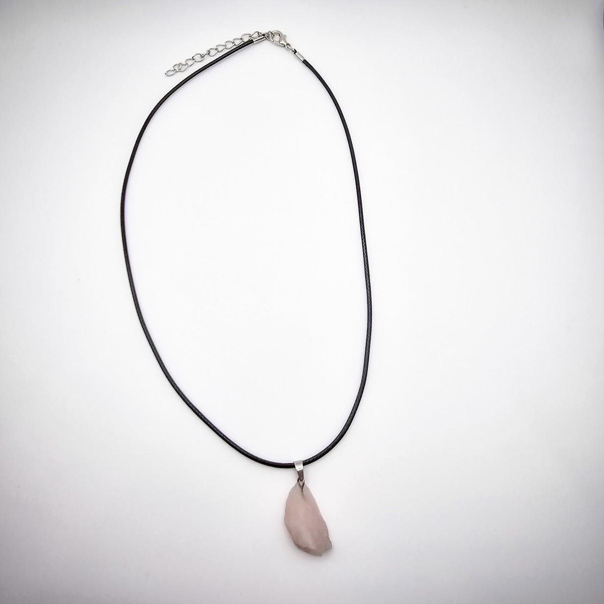 The entire Rose Quartz pendant necklace on a white background, showing the black cord and the pendant's natural elegance.