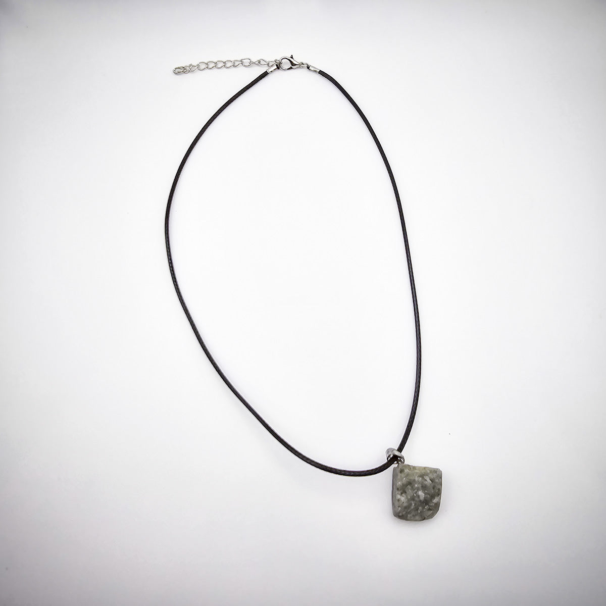 Entire Lapis Lazuli pendant necklace on white background, highlighting the black cord and stone's natural allure.