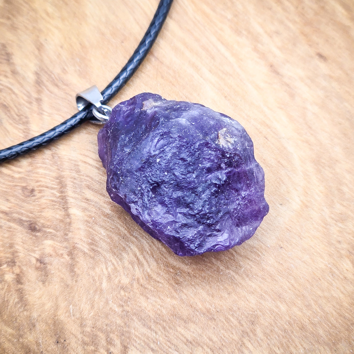 Close-up view of the Amethyst raw gemstone pendant, highlighting the stone's unique hues and textures.