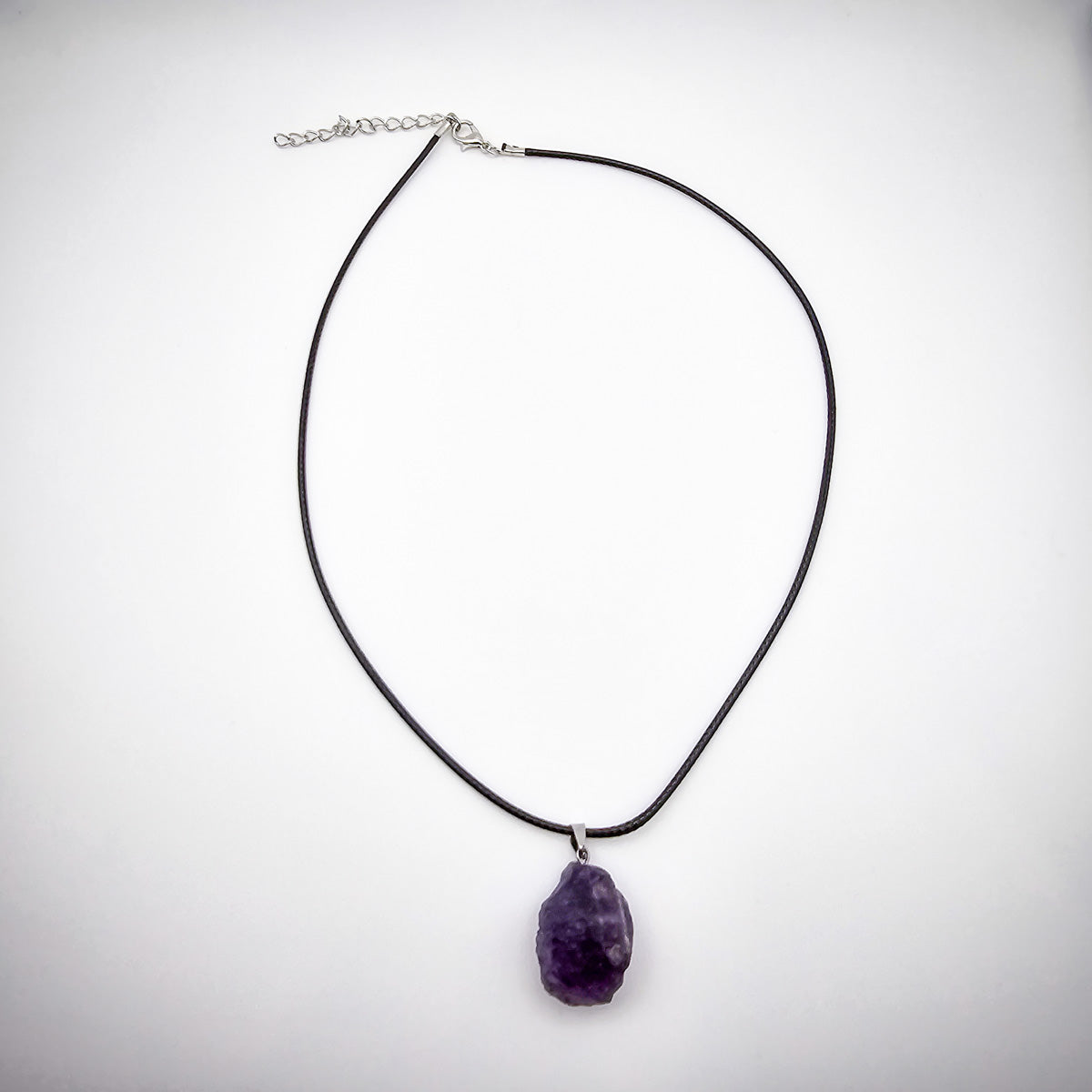 Full display of the Amethyst pendant necklace against a white background, emphasizing the elegance of the black cord and the gemstone's tranquil presence.