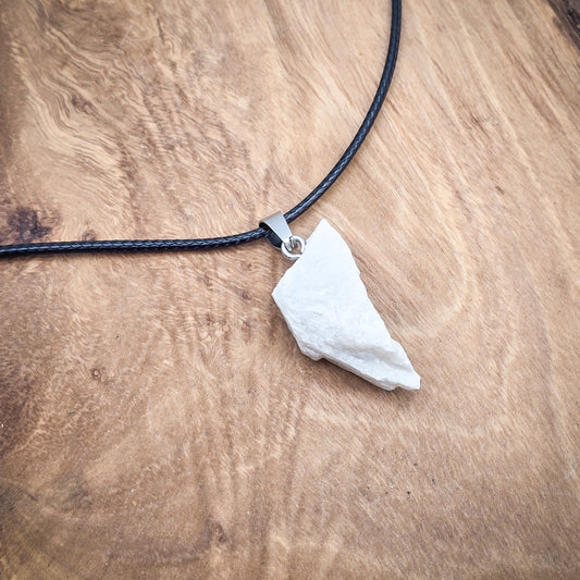 Moonstone raw gemstone pendant on black cord over wood, highlighting its natural luminosity and unique variations.