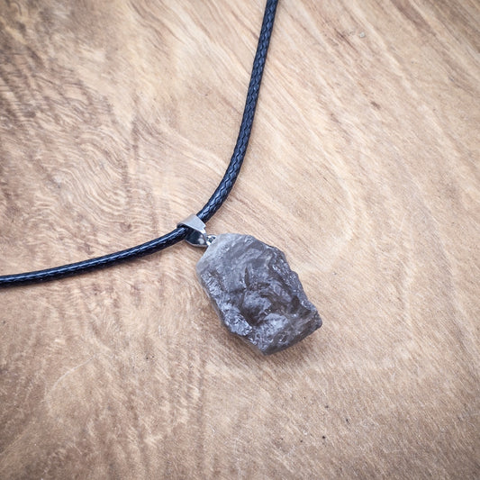 Smoky Quartz raw gemstone pendant on black cord, displayed on wood, highlighting its translucent smoky color and raw, natural allure.