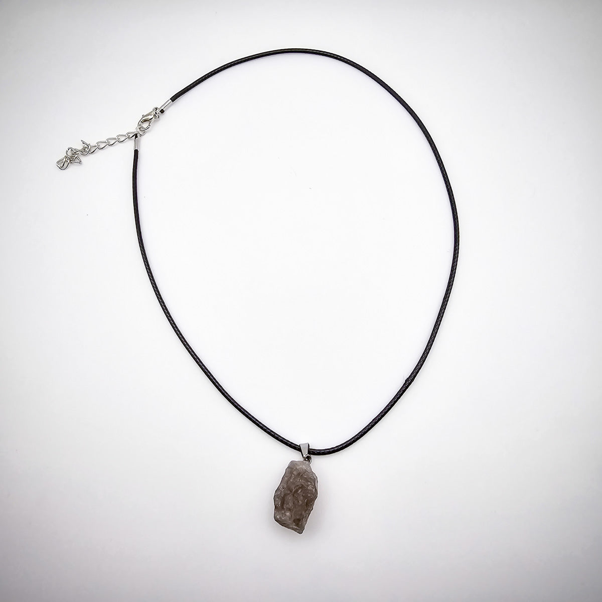 Full display of the Smoky Quartz pendant necklace against a white background, emphasizing the elegant simplicity of the black cord and the stone's grounding presence.