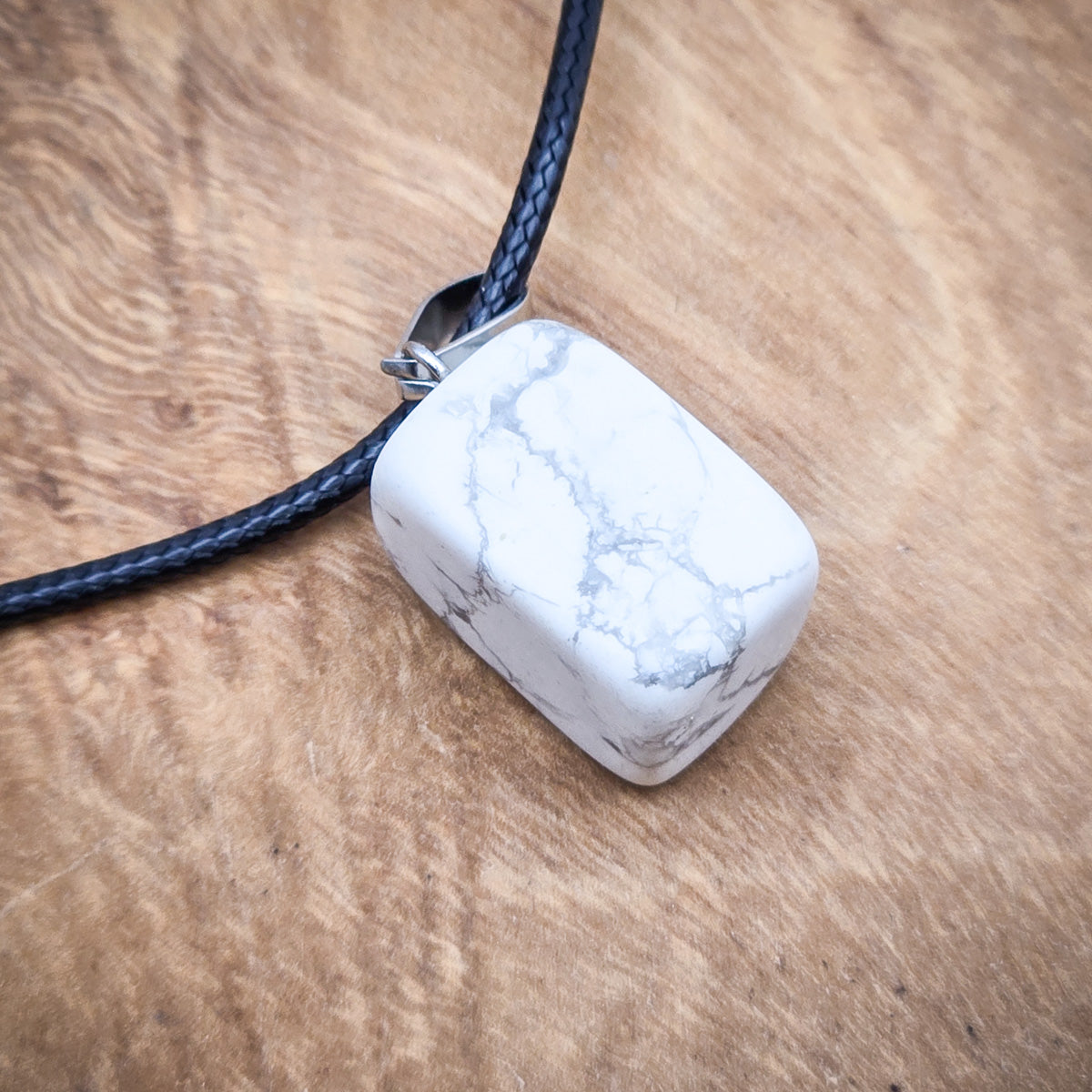 Close-up of the Howlite cube pendant, showcasing its unique marbling and polished, contemporary shape.