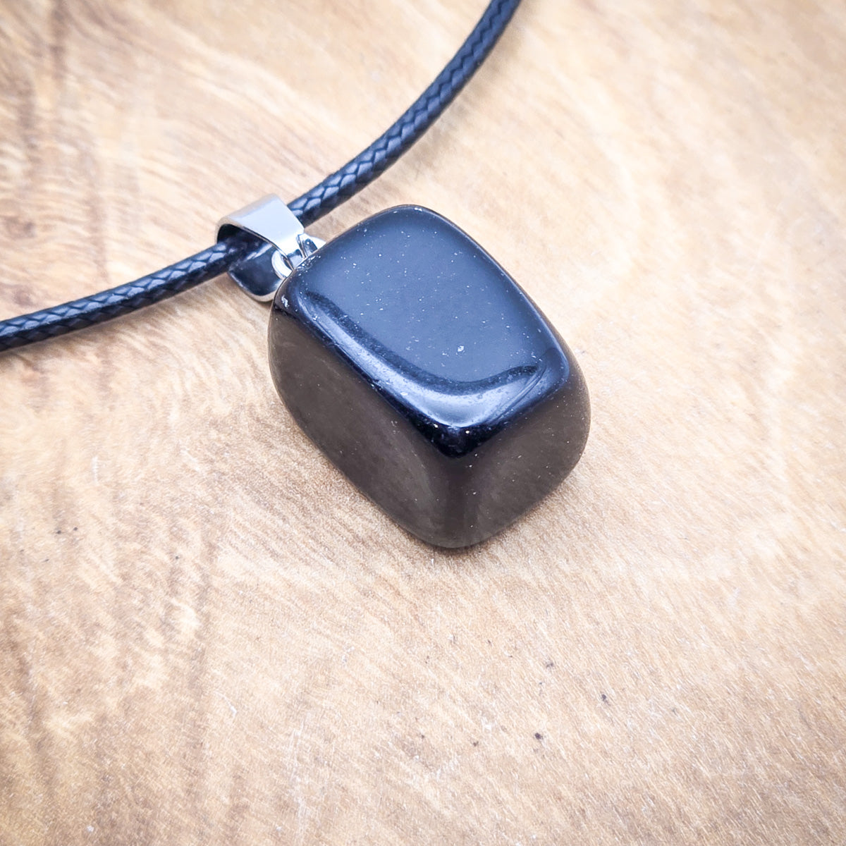 Close-up of the Onyx cube pendant, highlighting its smooth, polished surface and geometric precision.