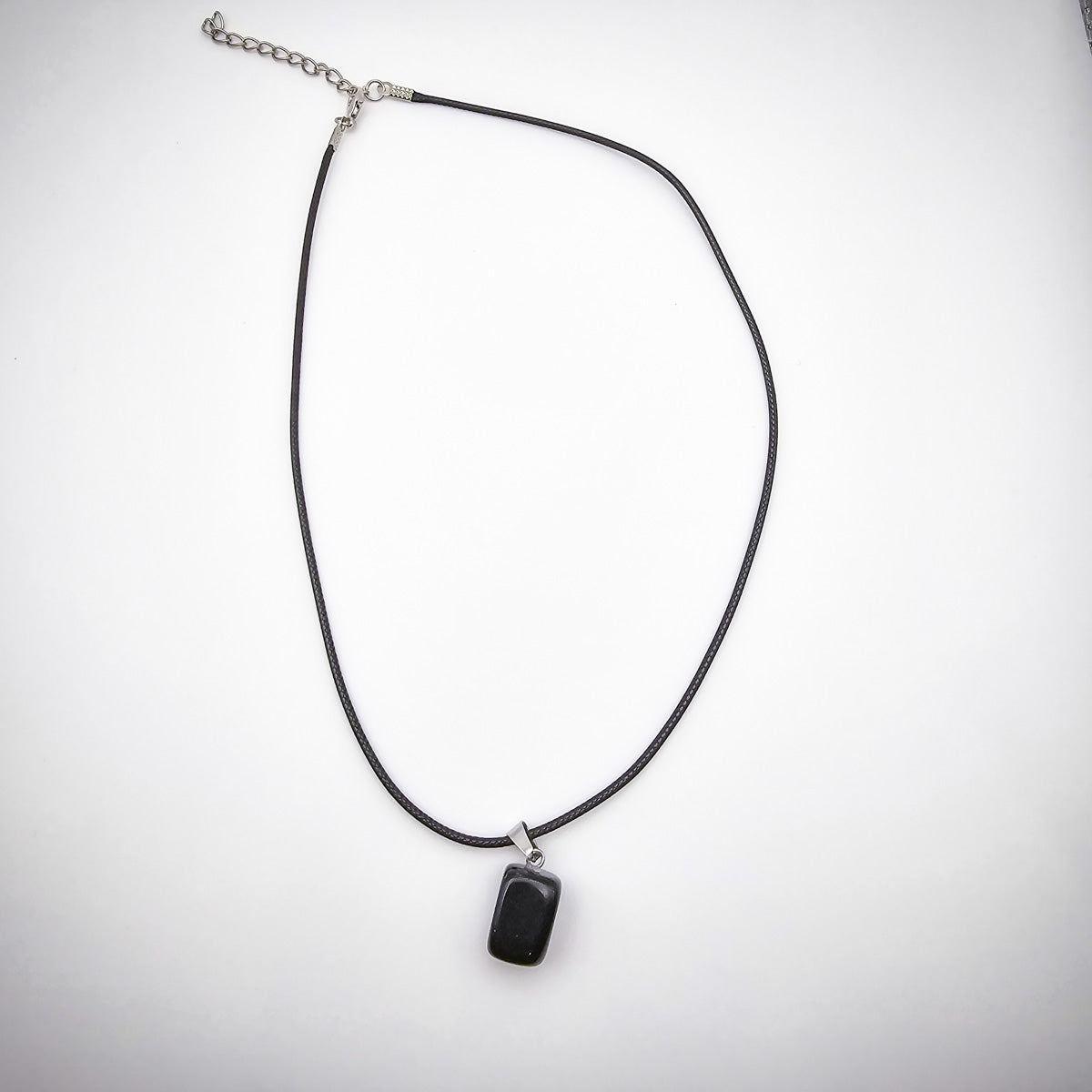 The entire Onyx cube pendant necklace against a white background, showcasing the minimalist design and the pendant's bold, protective essence