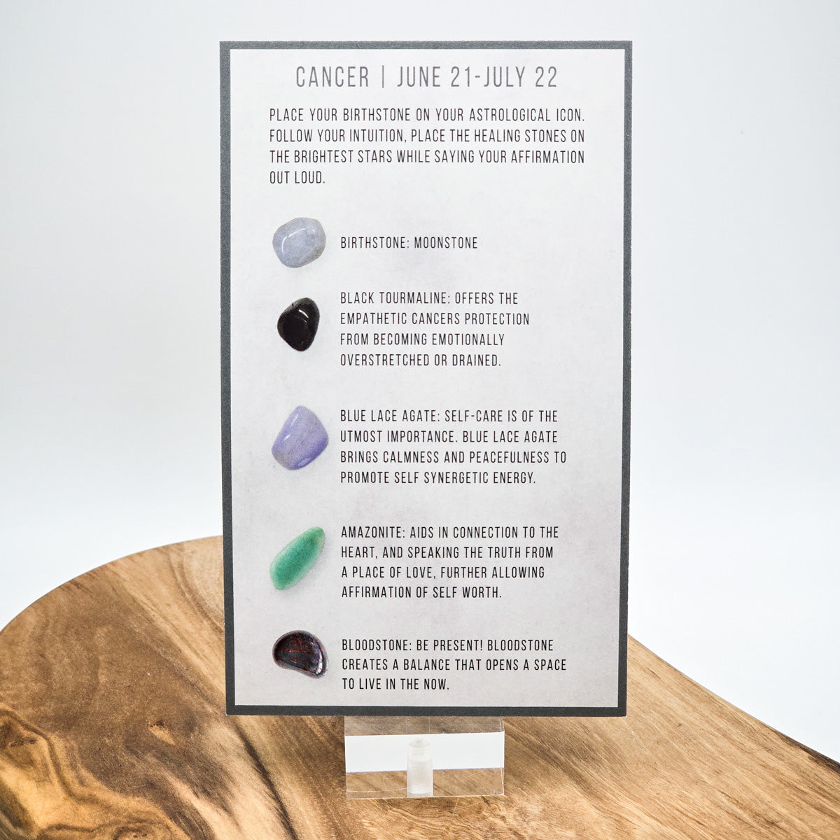 Reverse side of the Cancer card showing what crystals the bag contains.  Sitting on a wood block with white background.