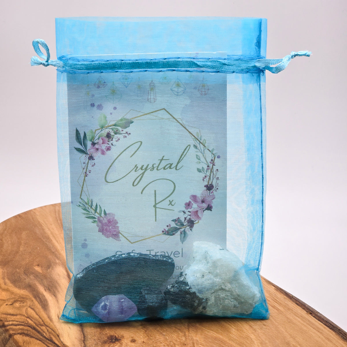 Assorted 'Safe Travel' Mojo Bag crystals and salts displayed on a wooden surface with a pristine white background, highlighting the variety of the contents.