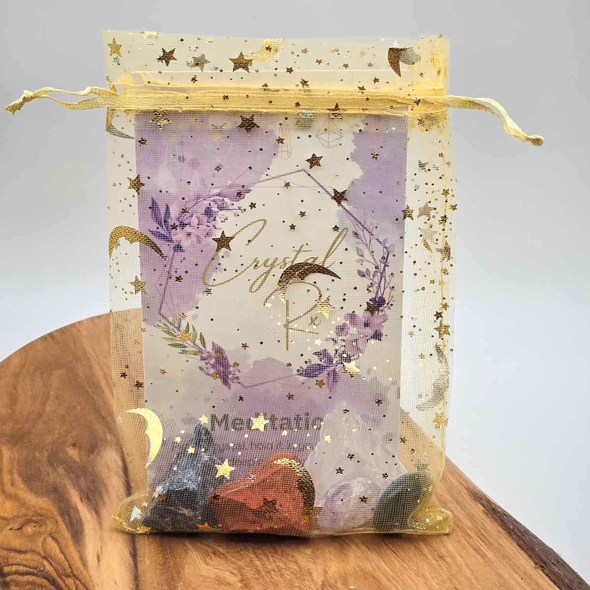 Meditation & Mindfulness' Mojo Bag on a wooden surface with its rich selection of enhancing crystals on display, against a clean white background.