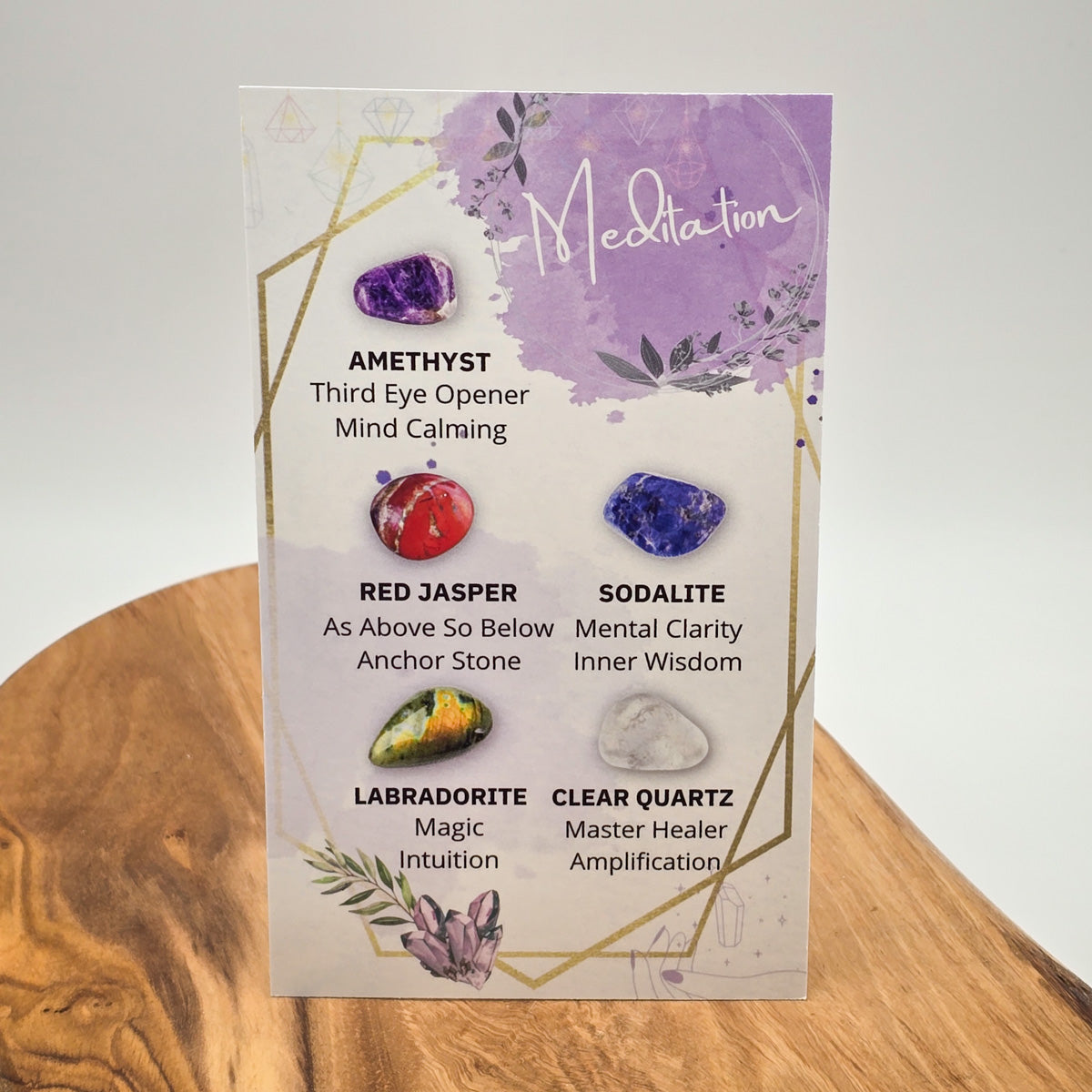 Back of the 'Meditation' card detailing the mindful qualities of each crystal, presented on a wooden backdrop with a pure white background for clarity.