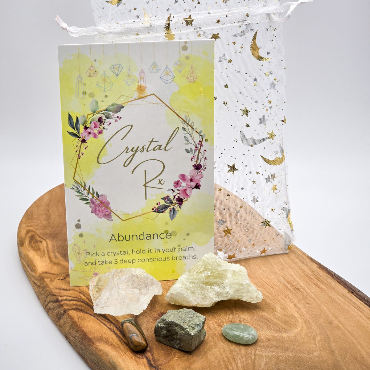 Full display of 'Abundance & Prosperity' Mojo Bag contents spread out on wood, showing Aventurine, Pyrite, Citrine, Quartz, and Tiger Eye stones.