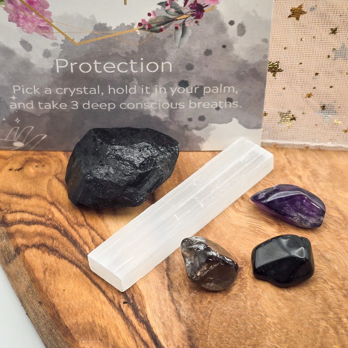 Closeup view of the 'Protection' Mojo Bag's crystals adjacent to the card bearing the title 'Protection,' reinforcing the theme of safeguarding energies.