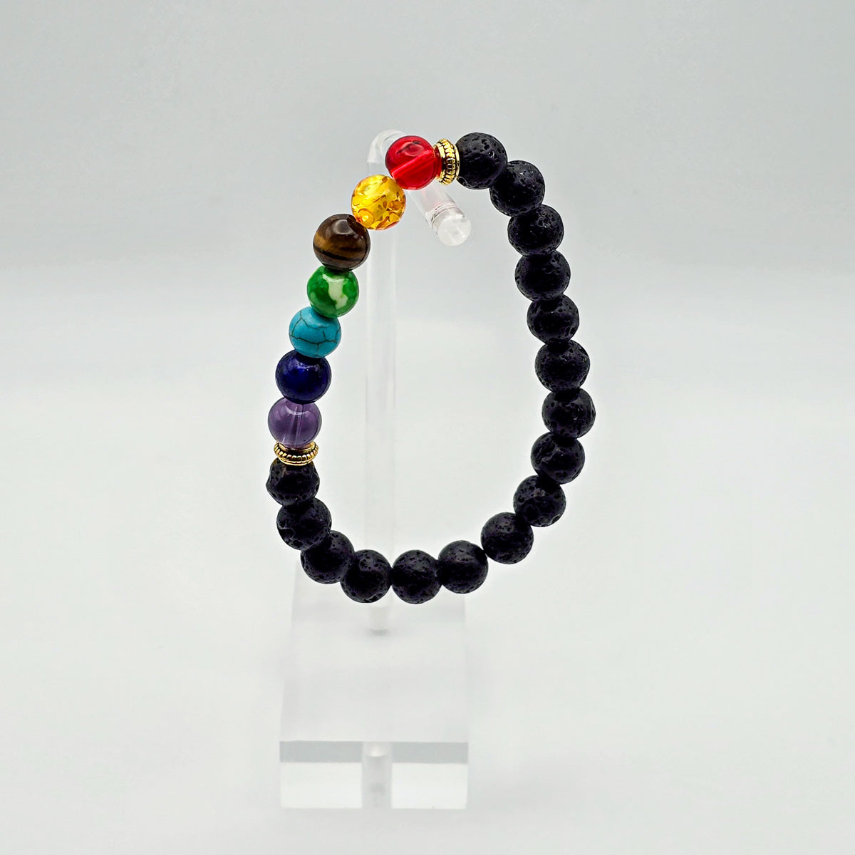 Lava stone chakra bracelet displayed on clear acrylic - holistic accessory