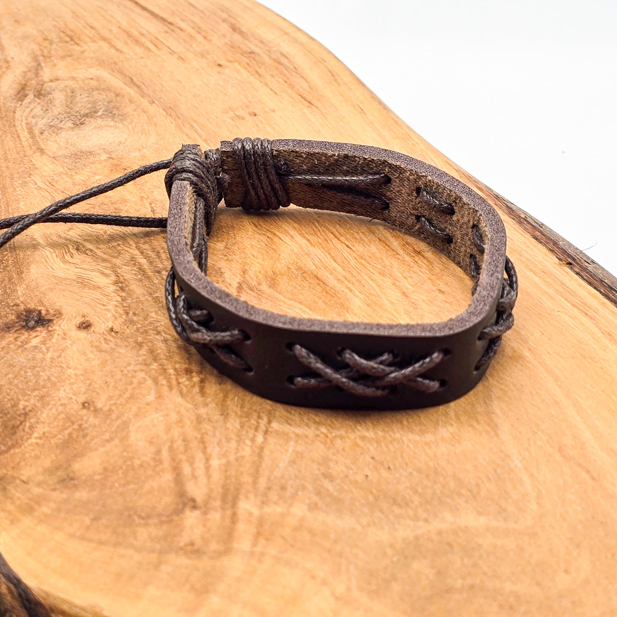 Detail of unisex leather bracelet on wood - refined craftsmanship brown leather