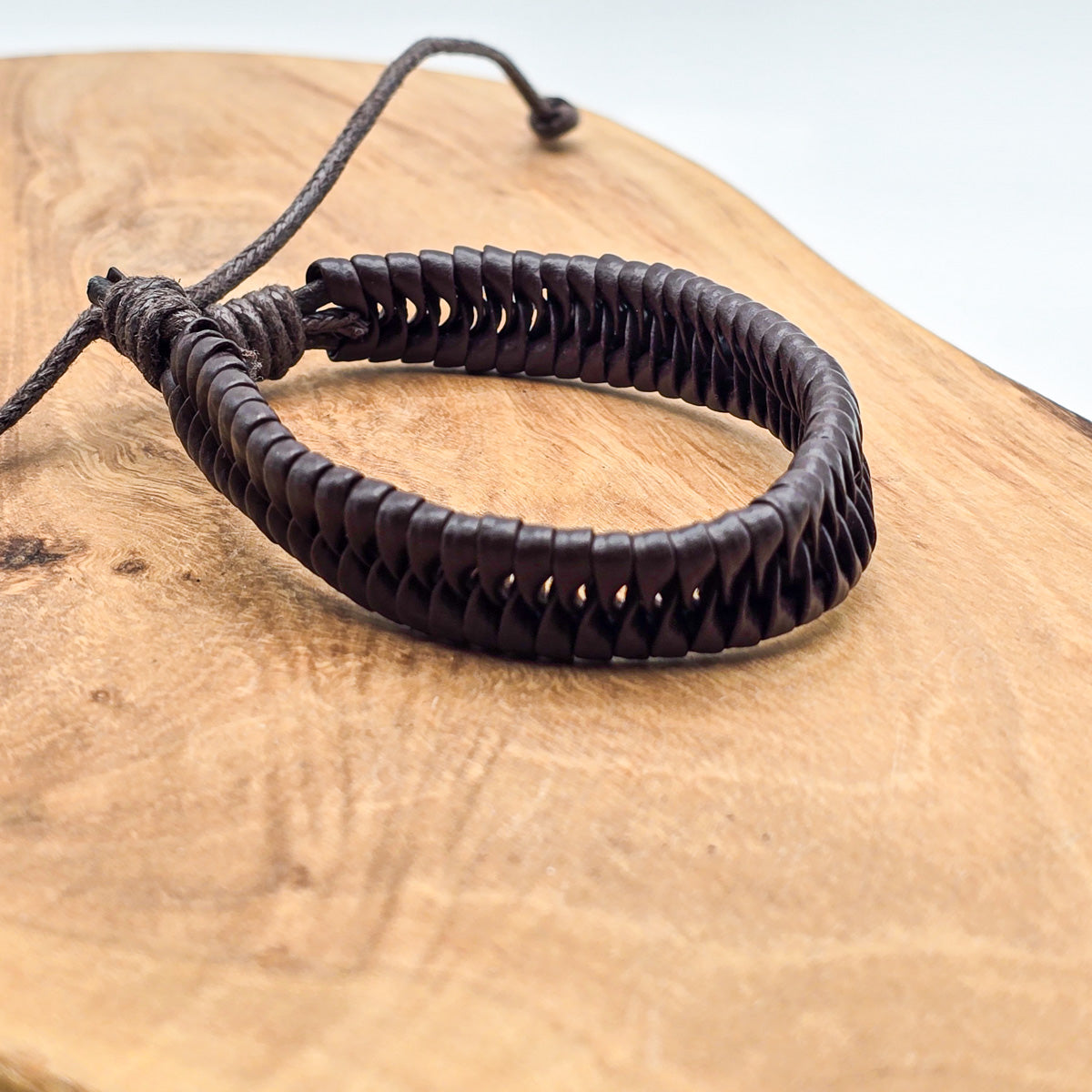 Detail of unisex leather bracelet on wood - refined craftsmanship brown leather