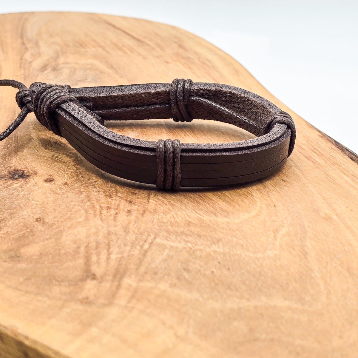 Detail of unisex leather bracelet on wood - refined craftsmanship, brown leather