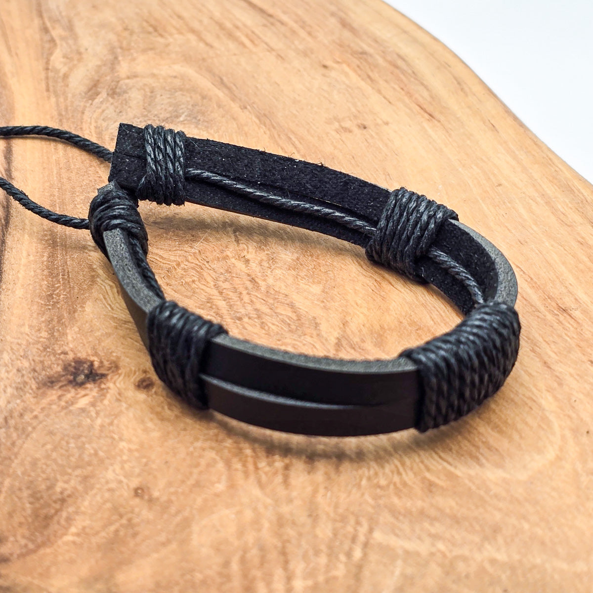 Detail of unisex leather bracelet on wood - refined craftsmanship black leather