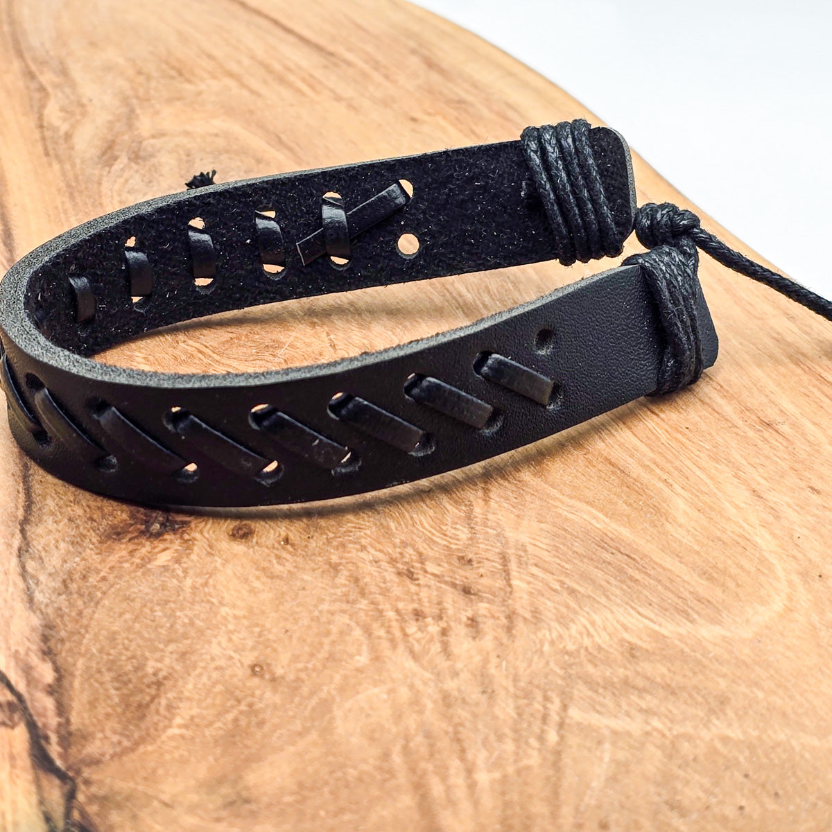 Detail of unisex leather bracelet on wood - refined craftsmanship black leather