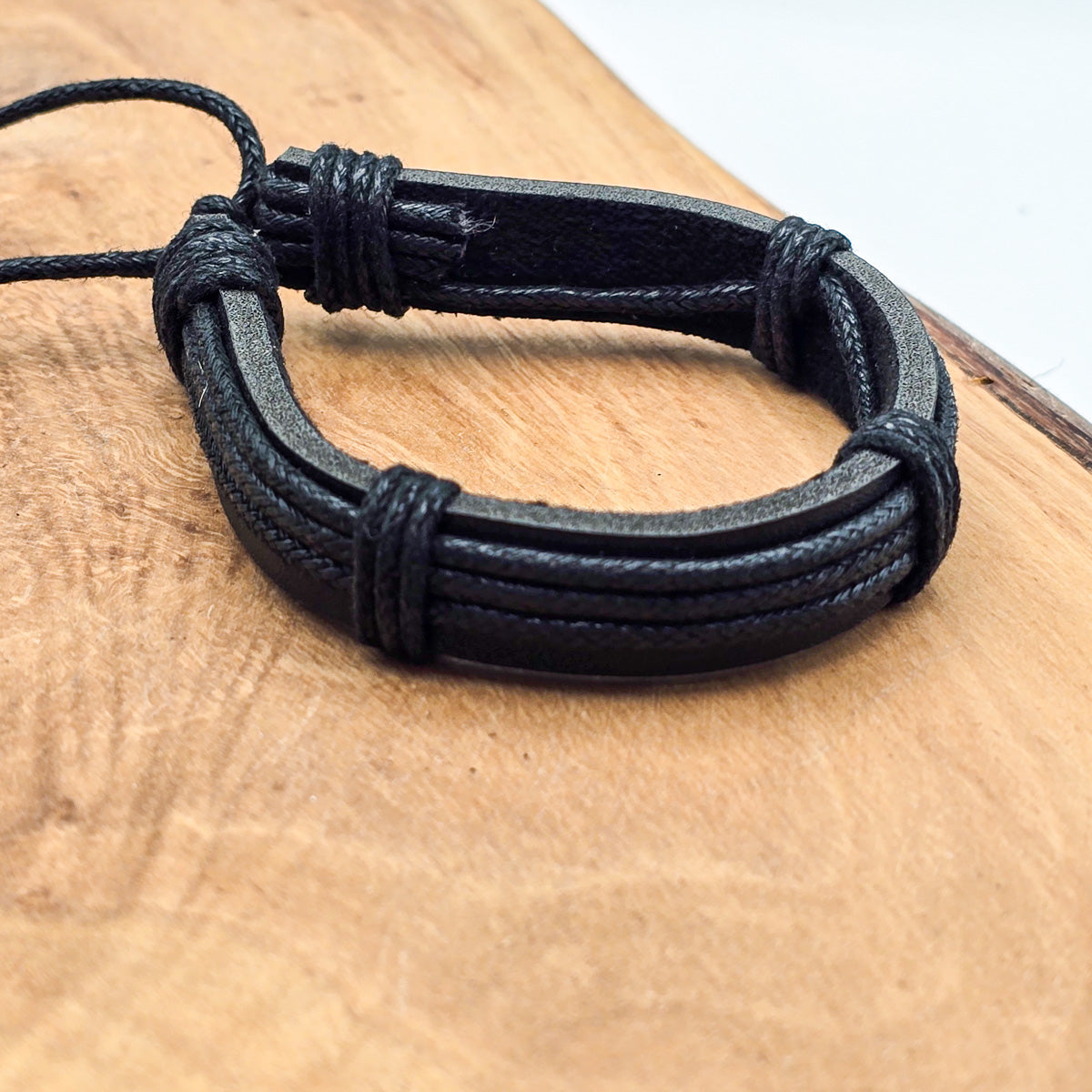 Detail of unisex leather bracelet on wood - refined craftsmanship black leather