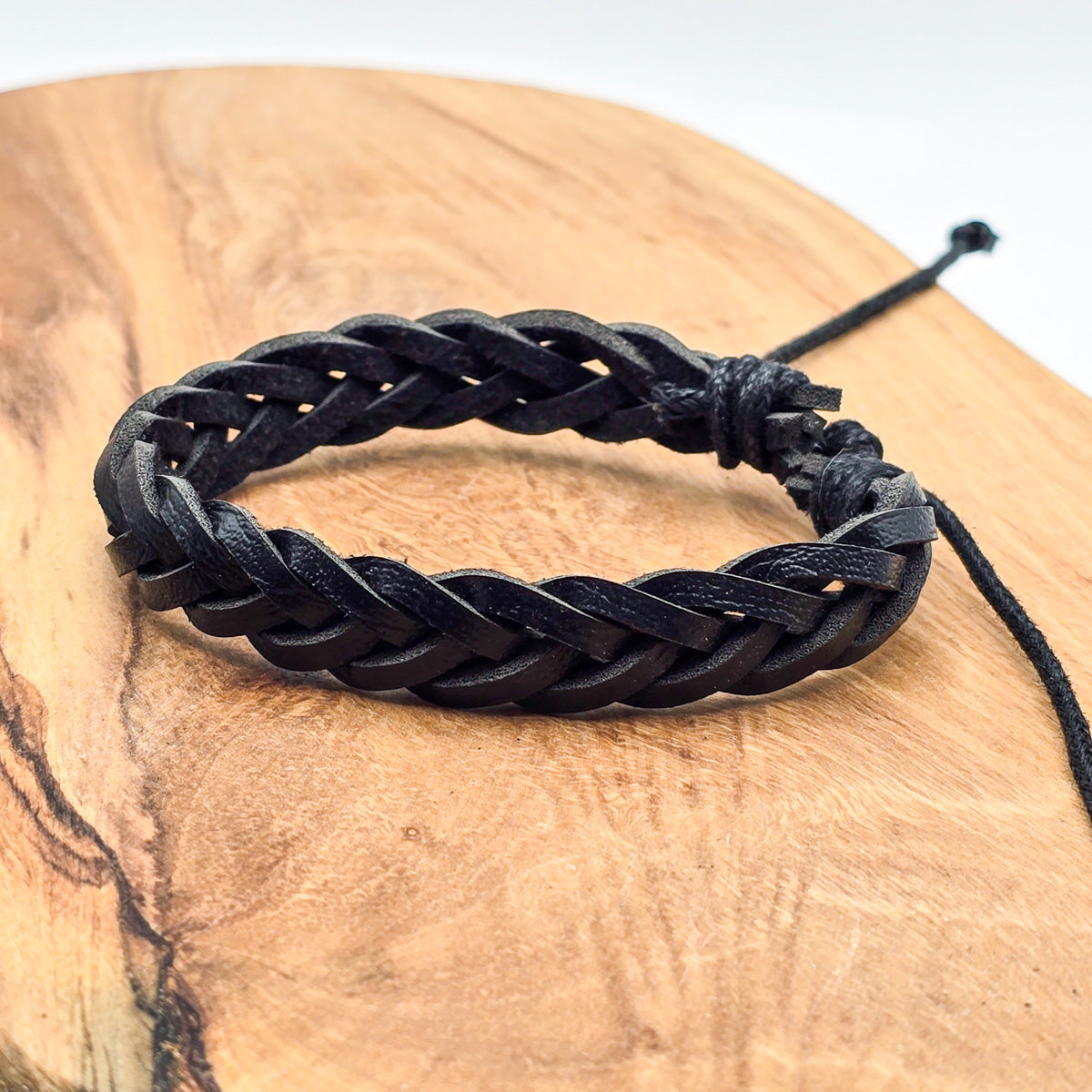 Detail of unisex leather bracelet on wood - refined craftsmanship black leather