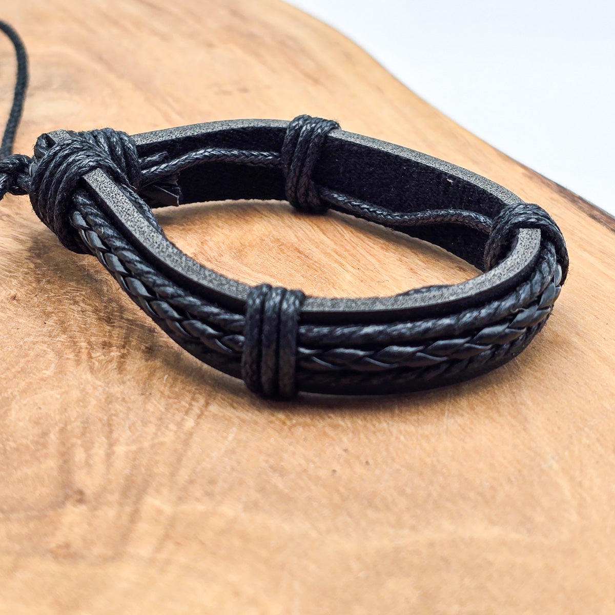 Detail of unisex leather bracelet on wood - refined craftsmanship black leather