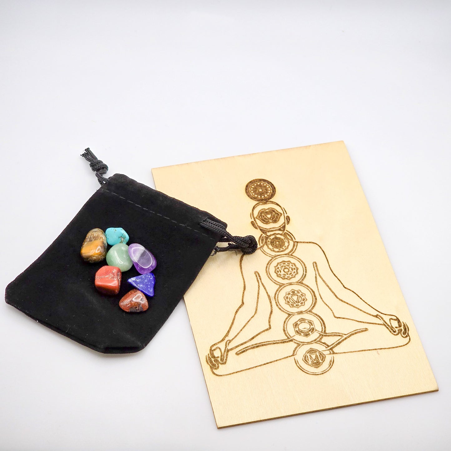 Chakra gridding board beside stones on velvet bag